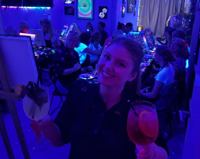 Vriendinnen proosten terwijl ze onder neonlicht schilderen